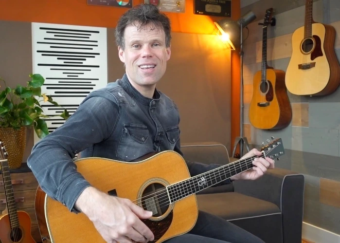 Jaap Kwakman met akoestische gitaar in de lesopstelling van Sixstrings