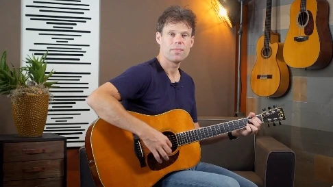 Jaap Kwakman speelt een liedje voor tijdens een gitaarles